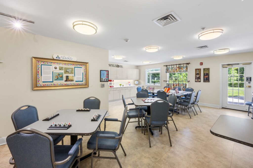 Game and craft room at Artis Senior Living of Huntingdon Valley with tables set up for tile games and painting, plus a display of resident artwork.