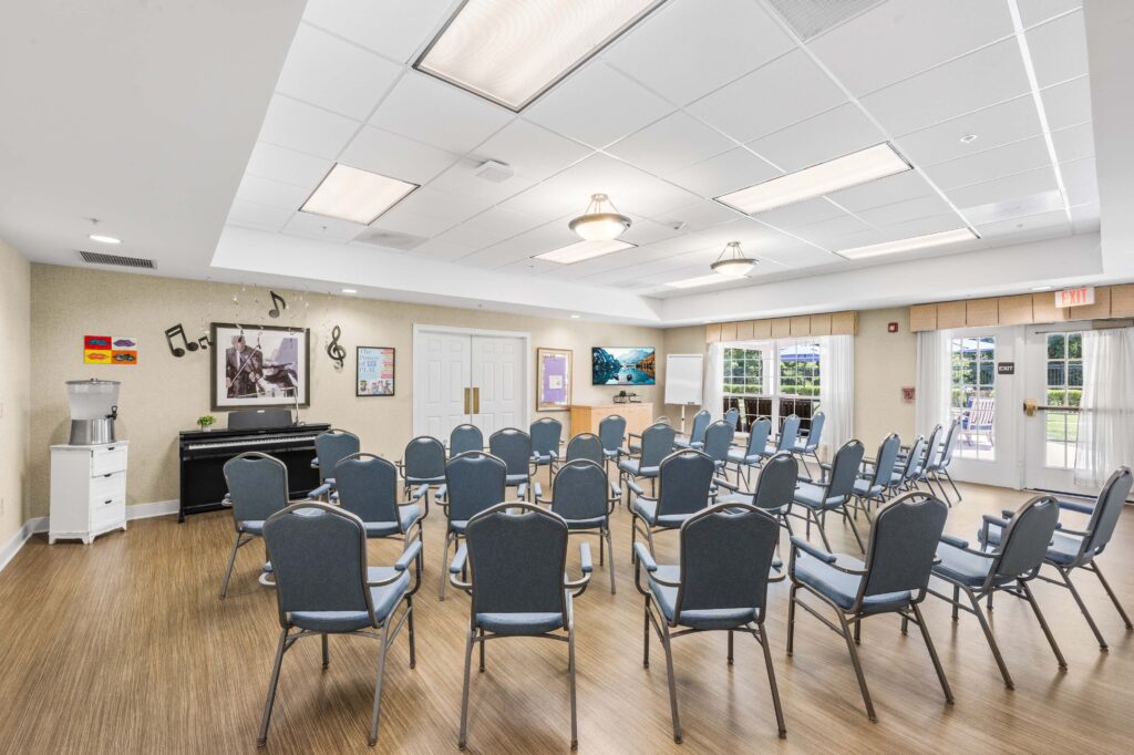 Music-themed activity room at Artis Senior Living of Huntingdon Valley with a digital piano, rows of chairs, and a wall-mounted TV.