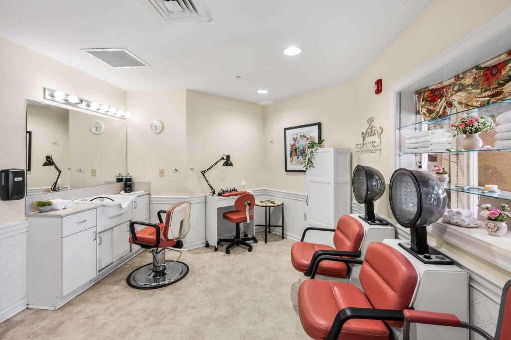 On-site beauty salon at Artis Senior Living of Huntingdon Valley with styling chairs, a wash sink, hair dryers, and a manicure station