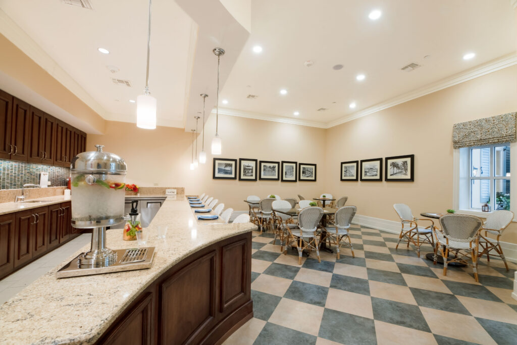 Bistro-style café at Artis Senior Living of Palm Coast with a checkered floor, bar seating, and café tables