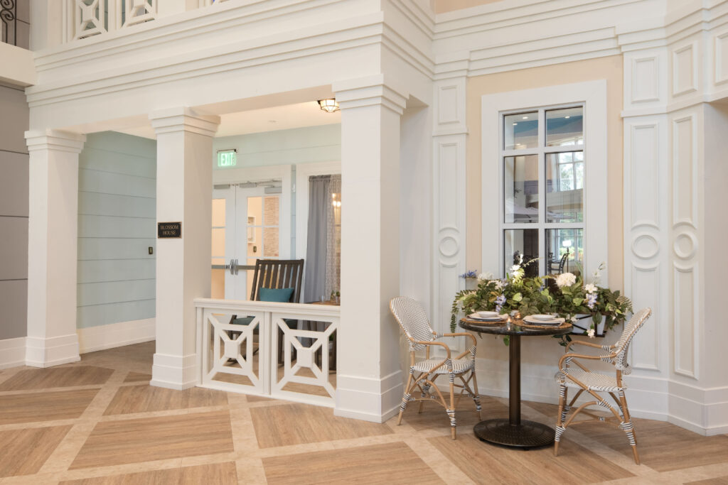 Elegant café-style seating area outside the Blossom House neighborhood at Artis Senior Living of Palm Coast, with a bistro table and floral centerpiece