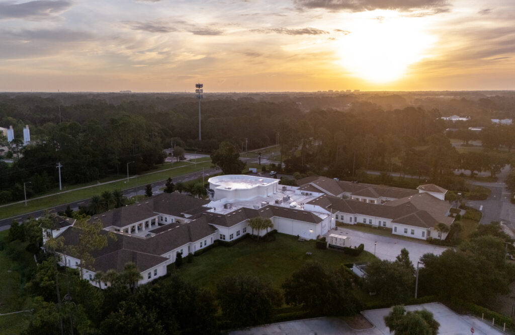 Aerial view of Artis Senior Living of Palm Coast campus at sunset, surrounded by wooded grounds near the community's residences
