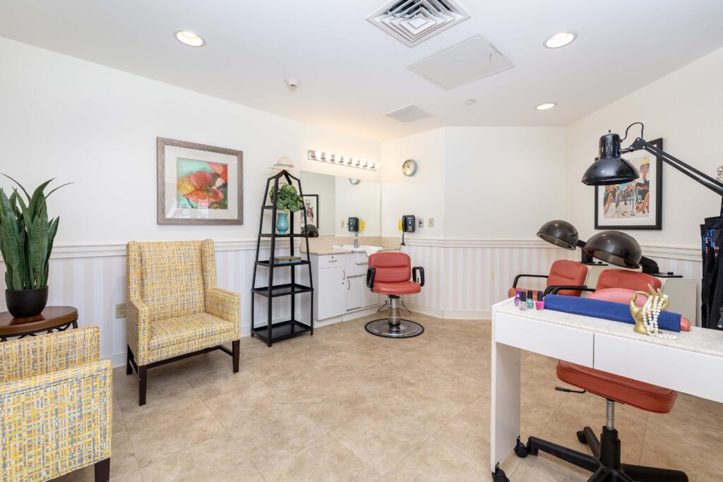 "On-site beauty salon at Artis Senior Living of Branford with styling chair, sink, hair dryers, manicure station, and comfortable waiting seating for residents